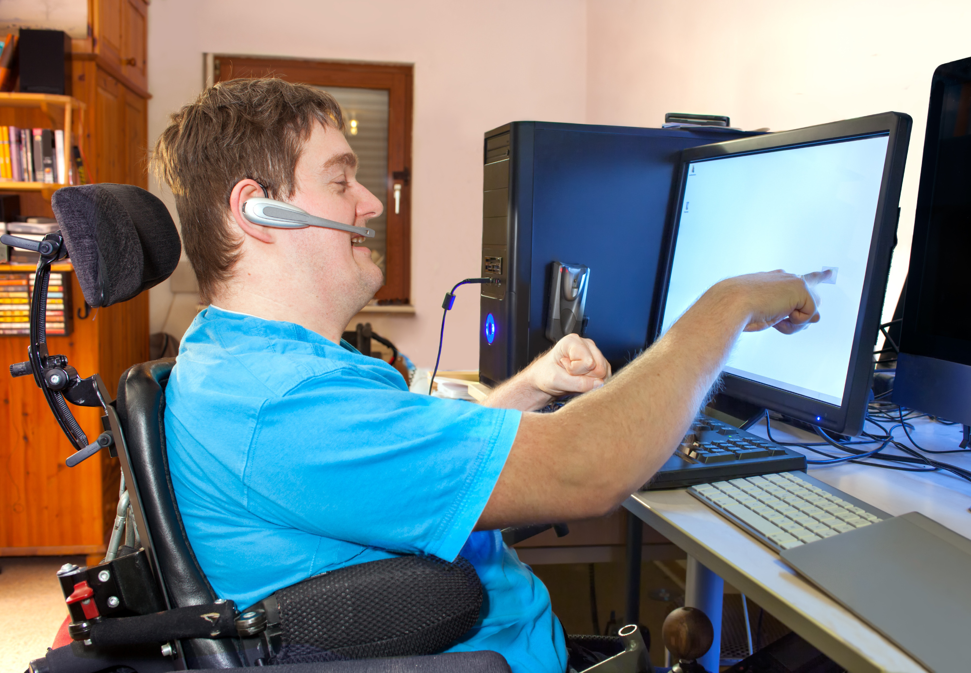 A disabled man in a wheelchair engaging and interacting with a PC set up